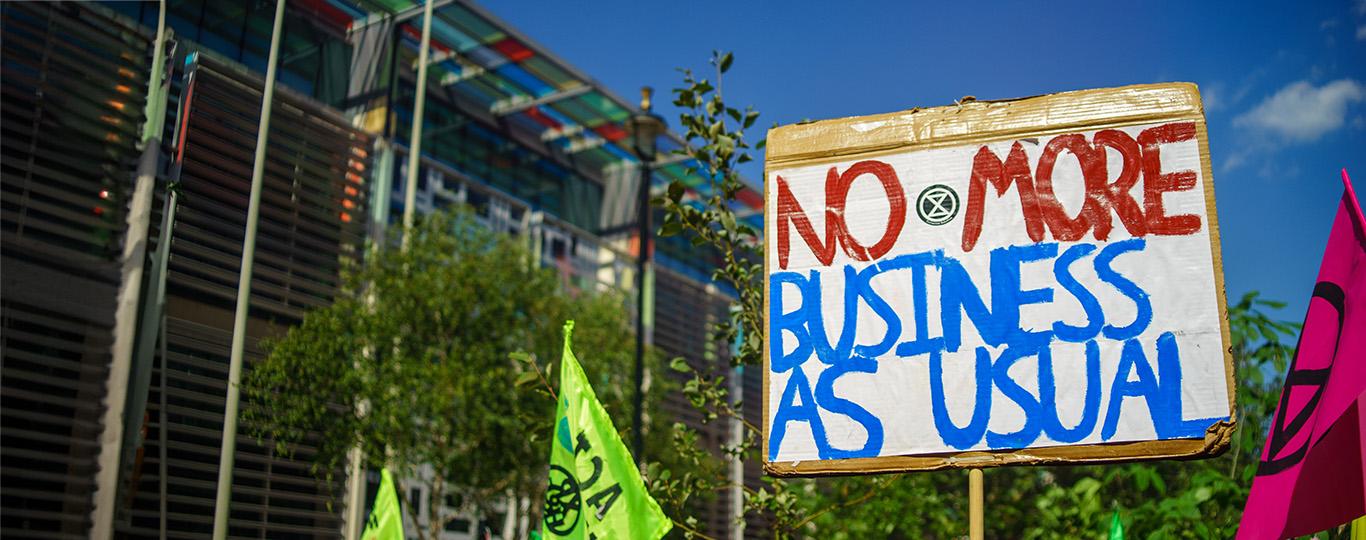 bord met opschrift 'no more business as usual' tijdens klimaatbetoging in Londen