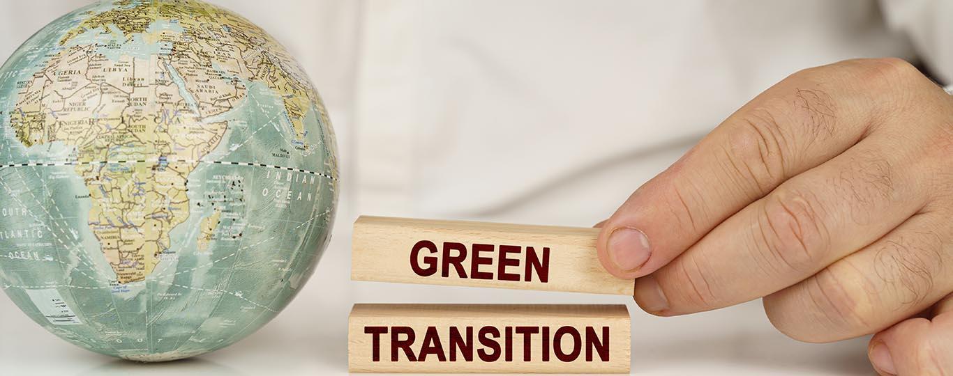 man stapelt blokjes met opschrift green transition naast een wereldbol