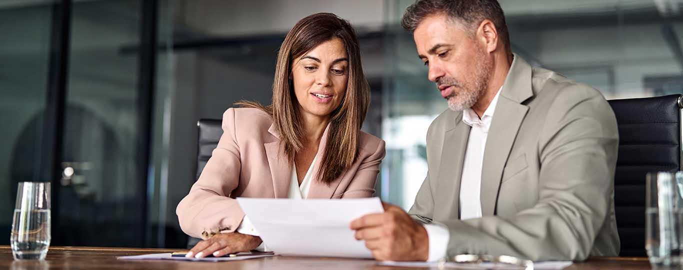 man en vrouw in bedrijfsomgeving bekijken samen een document