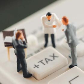 belastinghervorming: miniatuurmensen in discussie rond taxknop op rekenmachine