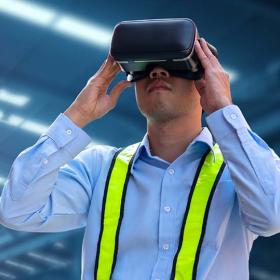 man met VR-bril in industriehal met robot op de achtergrond
