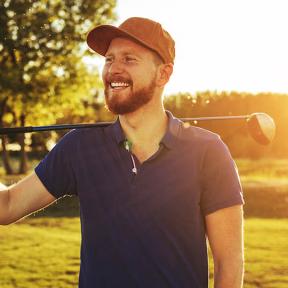 ontspannen man houdt golfstick op zijn schouder op een golfbaan